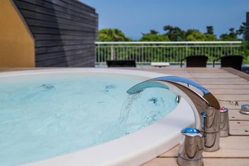 a hot tub with a faucet on a deck at Resort Hotel Moana Coast in Naruto
