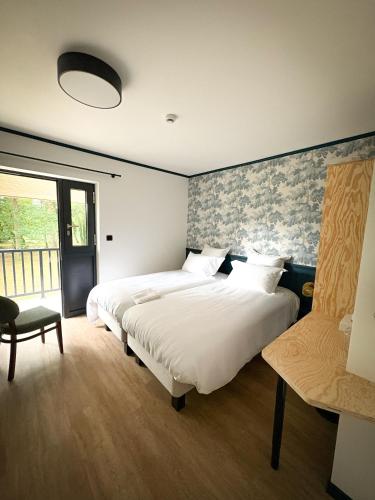 a bedroom with two beds and a chair at Hôtel du Golf De Jumièges in Le Mesnil-sous-Jumièges