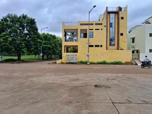 a yellow building in front of a parking lot at SHIVAY GUEST HOUSE & PG for short-stay near by BALCO MEDICAL CENTER,IIM, IIIT, HNLU, ITM, KALINGA UNIVERSITY, ADIWASI SANGHRALA,AND MANTRALAYA IN Naya raipur 