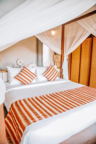 a large white bed with orange and white pillows at Menjaga Bay in Labuan Bajo