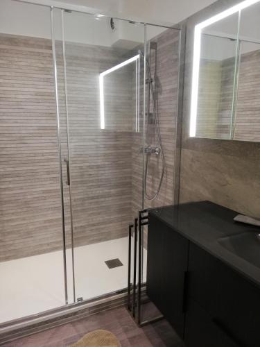 La salle de bains est pourvue d'une douche, d'un comptoir noir et d'un lavabo. dans l'établissement T2 Bormes les Mimosas - La Favière, à Bormes-les-Mimosas