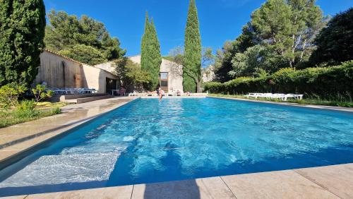 une piscine dans un jardin arboré et un bâtiment dans l'établissement Villa art de vivre & absolute calm Baux de Provence, aux Baux-de-Provence