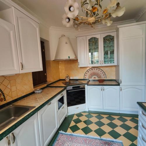 a kitchen with white cabinets and a checkered floor at Suite Di Bella Taormina in Roccalumera