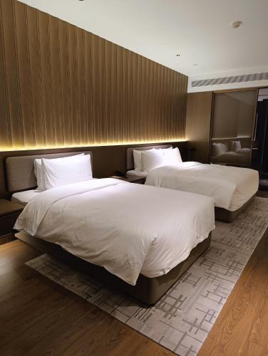 deux lits dans une chambre d'hôtel avec des draps blancs dans l'établissement Huaxia Royal Spring Resort Hotel, à Tangyin