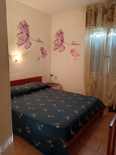 a bedroom with a bed with purple flowers on the wall at Domus Lavinia in Badesi