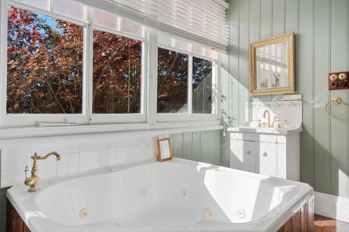 a white tub in a bathroom with two windows at Franklin Lodge, Huon Valley, Tasmania, Lavender Room in Franklin