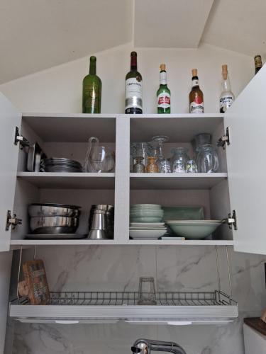 a kitchen shelves with bottles and dishes on them at Dongpirang Private Pension #jungangmarket #petfriendly in Tongyeong