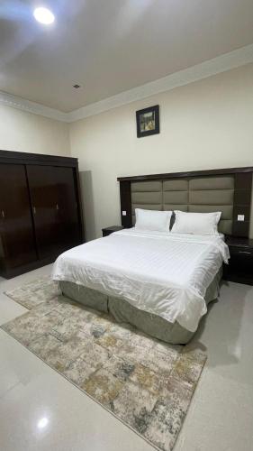 a bedroom with a large white bed and a rug at بسمة الفخامة للشقق المخدومة in Abu Arish