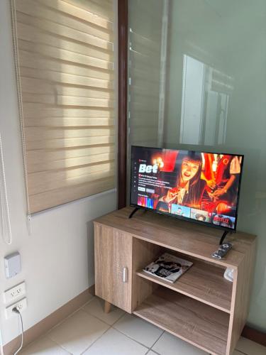 a flat screen tv on a wooden stand in a room at 40sqm Minimalist Condo w Balcony SM Marilao in Marilao