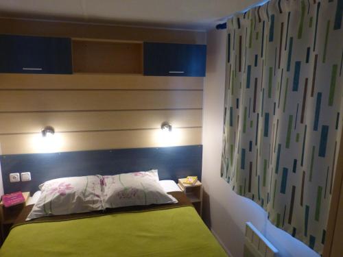 a bedroom with a bed with a green headboard at camping Le Clos de la Lère in Cayriech