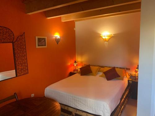 - une chambre avec un lit blanc aux murs orange dans l'établissement Aux Amandiers, à Fréjus