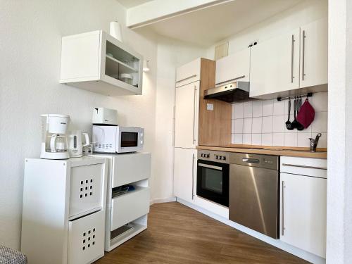 a white kitchen with white cabinets and appliances at Ferienwohnung De Krabb in Dorum