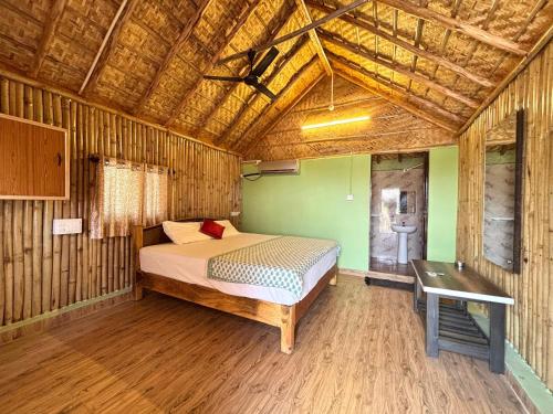 a bedroom with a bed and a table in a room at Mowgli's Cafe Hampi & Guest House in Hampi