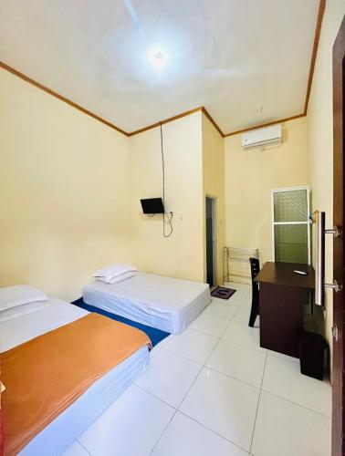 ein Hotelzimmer mit zwei Betten und einem Schreibtisch in der Unterkunft Victoria Homestay in Pulau Lutung