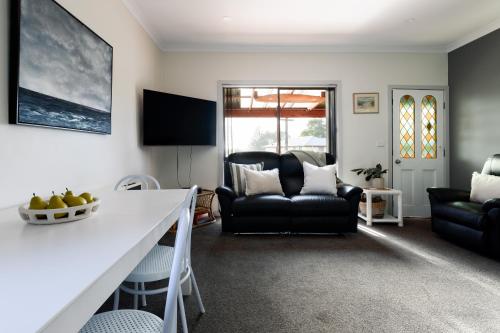 a living room with a black couch and a table at Family Comfort in the Stunning Sisters Beach in Sisters Beach