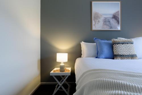 a bedroom with a bed and a table with a lamp at Family Comfort in the Stunning Sisters Beach in Sisters Beach
