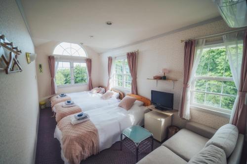 a bedroom with two beds and a tv and windows at 伊豆集 Episode IZU in Ito