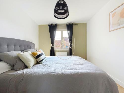 a bedroom with a large gray bed with pillows at La Tourelle des Rois in Dourdan