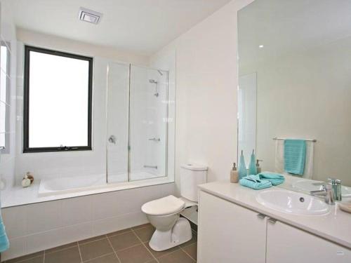 a white bathroom with a toilet and a sink at Coastal Comfort Pool, Golf, Beach, Room for 8 in Torquay