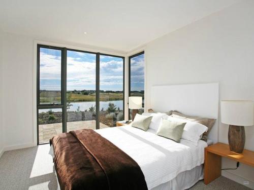 a bedroom with a large bed and large windows at Coastal Comfort Pool, Golf, Beach, Room for 8 in Torquay