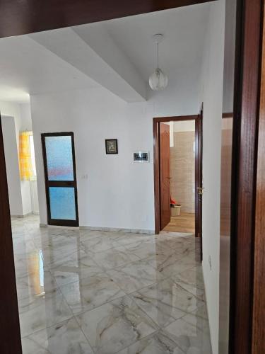 a living room with white walls and a marble floor at Vila Vako in Pogradec
