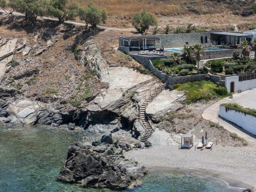 a house on a cliff next to a body of water at Zillion Villa - Sapphire Shores Beachfront Retreat by etouri in Panormos Rethymno