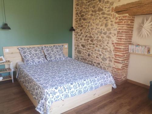 ein Schlafzimmer mit einem Bett und einer Ziegelwand in der Unterkunft Maison Pittoresque Terrasse et Jardin Monastir del Camp in Passa