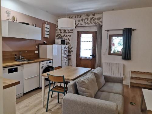 eine Küche und ein Wohnzimmer mit einem Tisch und einer Couch in der Unterkunft Maison Pittoresque Terrasse et Jardin Monastir del Camp in Passa