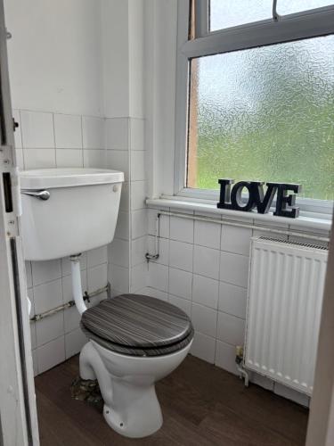a bathroom with a toilet and a window with the words love at 2 Bed Apartment Near Yeovil Hospital & Leonardo in Yeovil