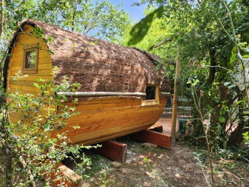 a log cabin with a thatched roof in the woods at Les Robinsonades in Couladère