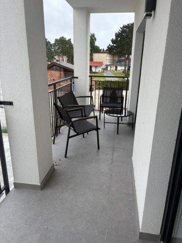 a balcony with chairs and tables on a building at Apartament Baltic 13 Mielno in Mielno