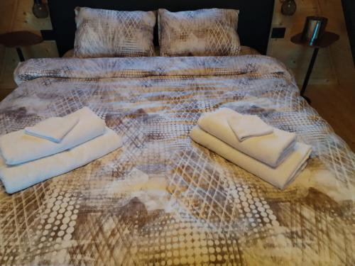 a bed with three towels on it at A Frame Vila sa Saunom Jakuzii i toplim bazenom in Koraćica