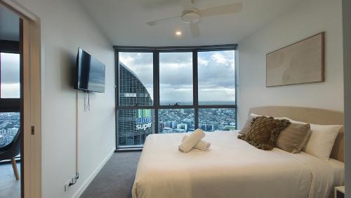 une chambre avec un grand lit avec une grande fenêtre dans l'établissement Queen's Wharf Apartments, à Brisbane