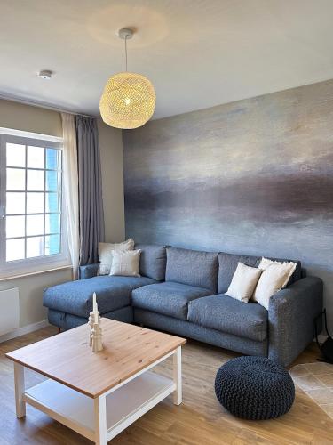ein Wohnzimmer mit einem blauen Sofa und einem Tisch in der Unterkunft L'Heurt Bleue - Maison de pêcheur face mer in Le Portel