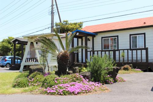 a small house with flowers in front of it at Jeju Feel House in Jeju