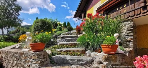 a garden with flowers and plants in front of a building at Komfortable Ferienwohnung Mit Garten Und Grill in Gleißenberg
