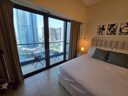 Un dormitorio con una cama y una ventana grande en Click Stay - JLT - Entire Studio & Balcony Lakes view Apartment -NA, en Dubái