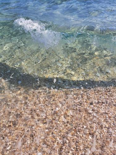 a body of water with rocks and the water at Captain's House Plomari in Plomarion