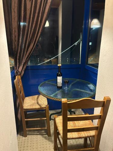 a table with a bottle of wine and two chairs at Captain's House Plomari in Plomarion