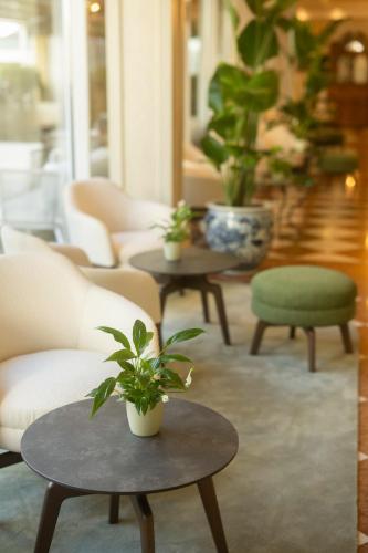 a living room with couches and tables with plants at Grand Hotel Liberty in Riva del Garda