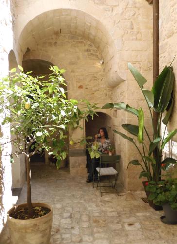 a woman sitting at a table in a room with plants at P43 Sicilian Suites in Ragusa