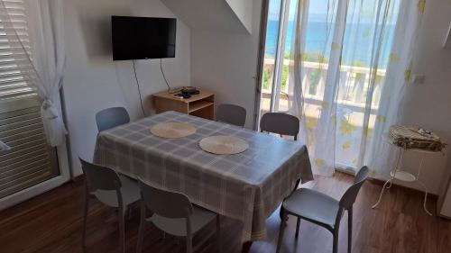 ein Esszimmer mit Tisch und Stühlen und einem Fernseher in der Unterkunft Apartments Zvonimir,place by the sea in Mirce