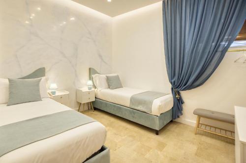 a bedroom with two beds and a window with blue curtains at L'Orchidea Blu in Pianillo