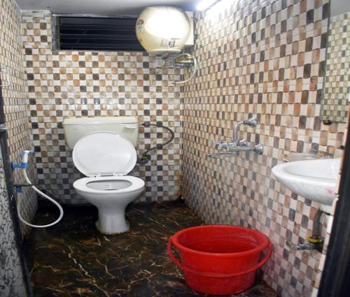 a bathroom with a toilet and a sink and a bucket at Sigmaa Stay Howrah in Sāntrāgāchi