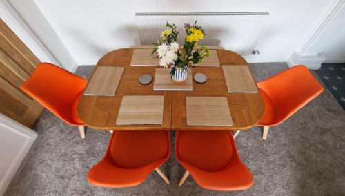 a wooden table with orange chairs and a vase of flowers at The Ransdale in Bridlington