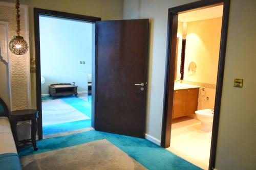 a bathroom with a door open to a bathroom with a toilet at Saraya Corniche Hotel in Doha