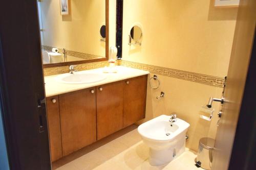 a bathroom with a sink and a toilet and a mirror at Saraya Corniche Hotel in Doha
