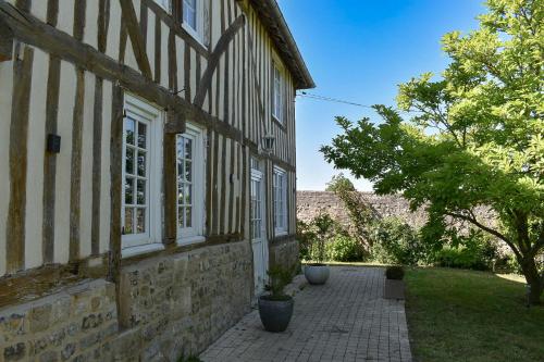 an old stone building with a walkway next to a yard at Au Clos de la Bergerie - campagne, détente & pétanque in Pont-lʼÉvêque