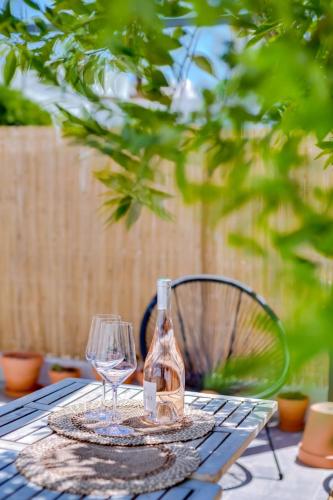 a table with a bottle and two glasses on it at Casa Bom Jardim by Enjoy your stay in Olhão