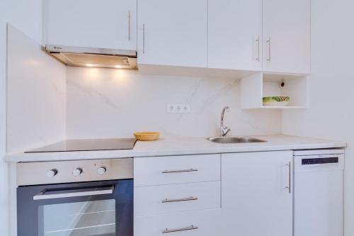 a white kitchen with white cabinets and a sink at Casa Bom Jardim by Enjoy your stay in Olhão